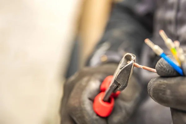 Les mains d'électricien tiennent les coupeurs de fil et le gros plan des fils. L'idée de réparer et de connecter le câblage électrique à la maison ou au travail — Photo