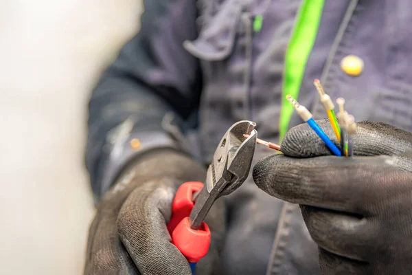 Les mains d'électricien tiennent les coupeurs de fil et le gros plan des fils. L'idée de réparer et de connecter le câblage électrique à la maison ou au travail — Photo