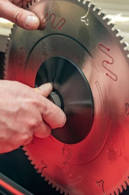 Saw disk çemberi kurulumu. Zanaatkar ahşap işçiliği makinesine dairesel testere bıçağı yerleştirir. Dairesel testere bakım ve ayarlama. Dikey fotoğraf.