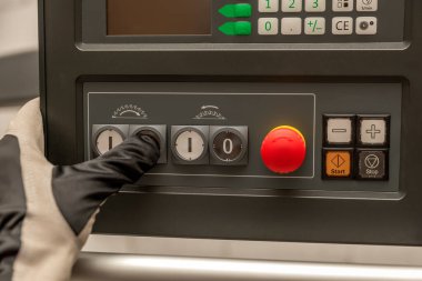 Bir fabrikadaki ahşap işçiliği makinesinin güç düğmesine el basar..