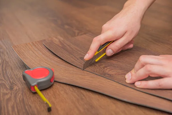 Pisos de vinilo DIY. Fácil instalación y corte con un cuchillo, Master corta tablón de vinilo antes de la instalación, suelo radiante marrón. Copiar espacio — Foto de Stock