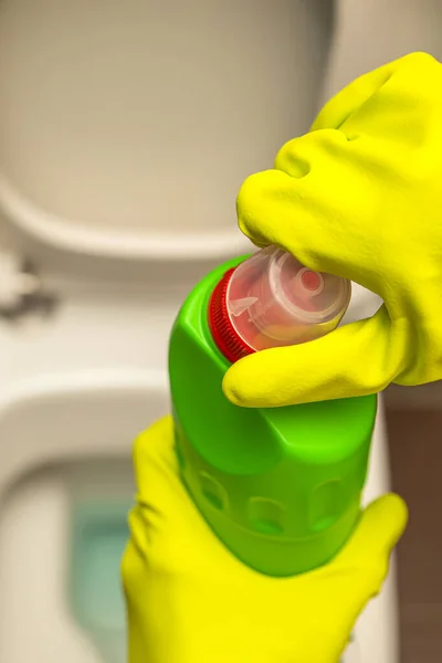 Limpeza e desinfecção de banheiros. Abra o limpador de toalete antes de usar. Uma mão enluvada limpa o banheiro com um desinfetante — Fotografia de Stock