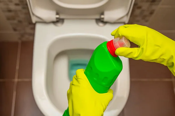 Cleaning and disinfection of toilets. Open the toilet cleaner before use. A gloved hand cleans the toilet with a disinfectant