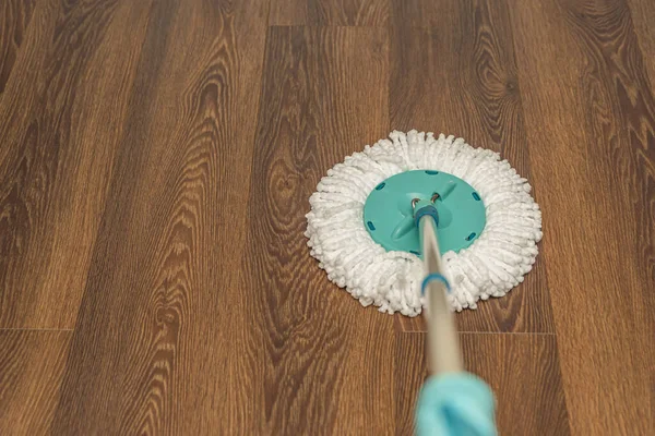 Floor cleaning and disinfection, house wet cleaning. Washing vinyl brown floor with a round mop, house cleaning, place for text