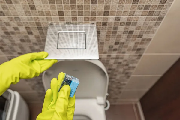 Lavador de cubos de toalete na mão. Uma mão abaixa um cubo desinfetante na água de um vaso sanitário embutido na parede. — Fotografia de Stock