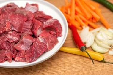 Ahşap arka planda pilav pişirmek için gerekli malzemeler. Tahta kesme tahtasının üzerinde soğan, biber, havuç, kıyma. Evde pilav pişirmek