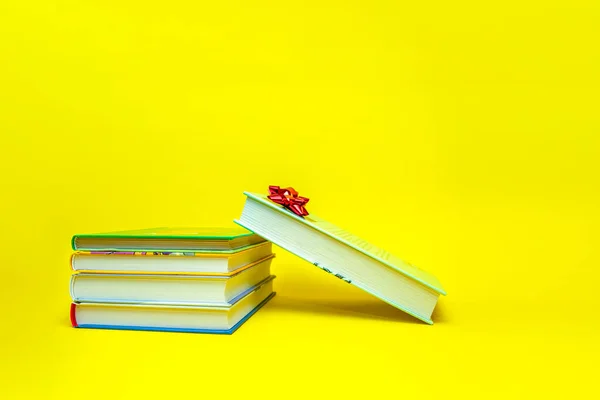 Τα βιβλία ως δώρο. Βιβλία με τόξο δώρου στοιβάζονται σε κίτρινο φόντο. Τόπος για κείμενο, πανό για εκτύπωση, σχεδιασμός καρτ ποστάλ. — Φωτογραφία Αρχείου