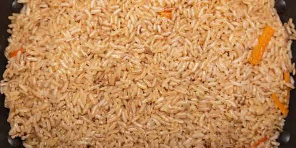 Pilaf-ris på nära håll. Orientaliskt kökskoncept. Nationell uzbekisk pilaf med kött i en gjutjärnspanna. Ovanifrån, lamm, devzira ris. — Stockfoto