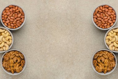 Farklı türde fındıklar, üst görünüm. Karışık fındıklar taş bir tezgahın üstündeki kaselerde yatıyor. Tasarım ve baskı için. Metin, tarif veya girdi eklenecek yer.