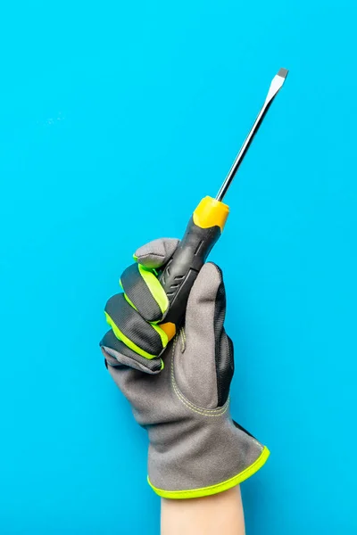 Κατσαβίδι. Κίτρινο και μαύρο κατσαβίδι στο χέρι ηλεκτρολόγου σε μπλε φόντο. Εργαλείο επισκευής και εγκατάστασης. Κάθετη φωτογραφία για το σχεδιασμό και την εκτύπωση δομικών θεμάτων. — Φωτογραφία Αρχείου