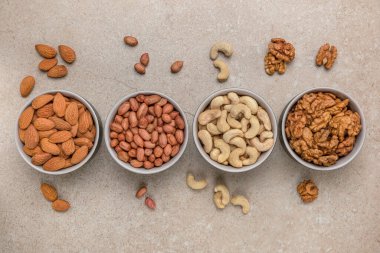 Ceviz arkaplan. Büyük format baskı, reklam ve web sitesi tasarımı için pankart. Farklı türde fındıklar, taştan bir tezgahın üstünde, üst tarafta kaselerde bulunur. Fıstık, fıstık, badem, ceviz..