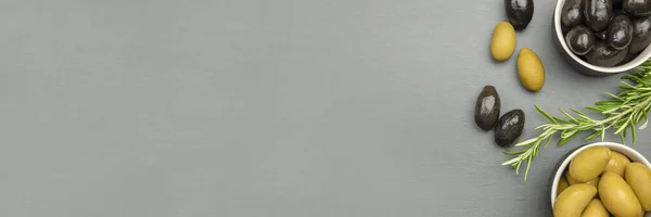 Aceitunas negras y verdes. Bella di cerignola Aceitunas italianas. Las aceitunas de color y una ramita de romero se encuentran en una encimera de piedra negra. Banner o póster culinario para publicidad con lugar para texto —  Fotos de Stock