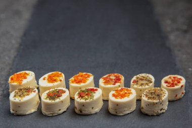 Baharatlı peynir tabağı. Farklı baharatlı Mazzarella peyniri. Siyah bir tepside çeşitli aromalı peynirli atıştırmalıklar. arkaplan ya da yiyecek ve atıştırmalık teması üzerine afiş