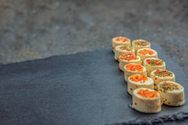 Baharatlı peynir tabağı. Farklı baharatlı Mazzarella peyniri. Siyah bir tepside çeşitli aromalı peynirli atıştırmalıklar. arkaplan ya da yiyecek ve atıştırmalık teması üzerine afiş