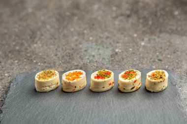 Baharatlı peynir tabağı. Farklı baharatlı Mazzarella peyniri. Siyah bir tepside çeşitli aromalı peynirli atıştırmalıklar. arkaplan ya da yiyecek ve atıştırmalık teması üzerine afiş