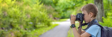 Kameralı bir turist. Kameralı bir çocuk parkta doğanın fotoğraflarını çekiyor. Genç bir fotoğrafçı parkta bir bankta oturur ve doğanın resimlerini çeker. Bir kamerayla seyahat etmek.