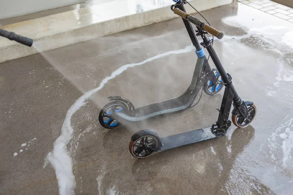 Lavando un scooter sucio en un lavadero de autos bajo agua a alta presión. Cuidado y limpieza del scooter —  Fotos de Stock