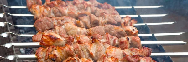 Churrasco de cozinha, churrasco de carne grelhada. Cozinhar shashlik de porco em espetos de metal. A fumaça das brasas se acumula sobre o prato. Banner publicitário com espaço de cópia — Fotografia de Stock