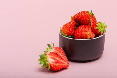 Pembe arka planda çilekler. Pembe arka planda bir fincan tabağında olgun çilekler. Metin eklenecek yer