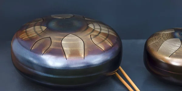 Steel tongue, drum. Singing bowl, steel drum and drumsticks. Instrument for sound wave therapy and meditation, healing.