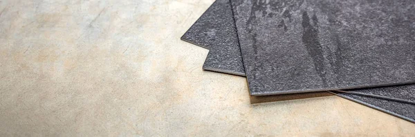 Sol en PVC vinyle. La texture du sol en vinyle est noire. Échantillons de revêtement en vinyle, carreaux de PVC noir sur le sol en béton avant l'installation. — Photo