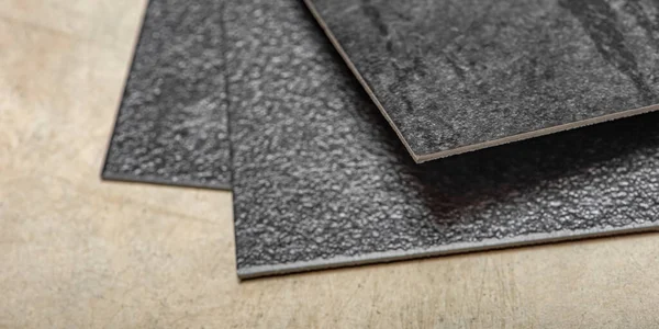 Suelo de PVC de vinilo. La textura del suelo de vinilo es negra. Muestras de revestimiento de vinilo, azulejos de pvc negro en el suelo de hormigón antes de la instalación. — Foto de Stock