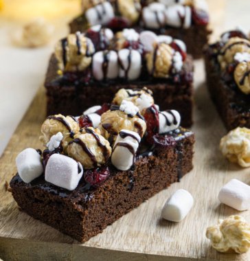 Çikolata, kar taneleri, kızılcık, lokum ve patlamış mısırla süslenmiş Noel brownileri. Noel tatlısı.