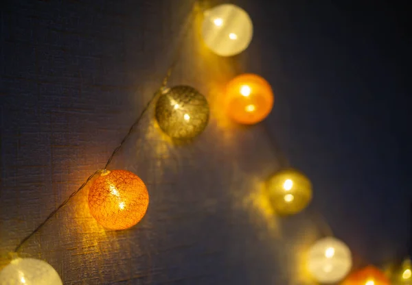 A festive garland of cotton balls glows in the dark. Christmas decorations. New Year. Dark photography.