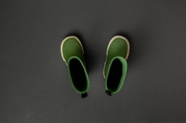 Koyu gri arkaplanda yeşil lastik çizmeler.