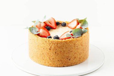 Beyaz arka planda taze çilek ve yaban mersiniyle süslenmiş ev yapımı klasik New York peynirli keki.