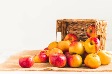 Beyaz arka plandaki hasır sepette taze sarı ve kırmızı elmalar. Sonbahar hasadı