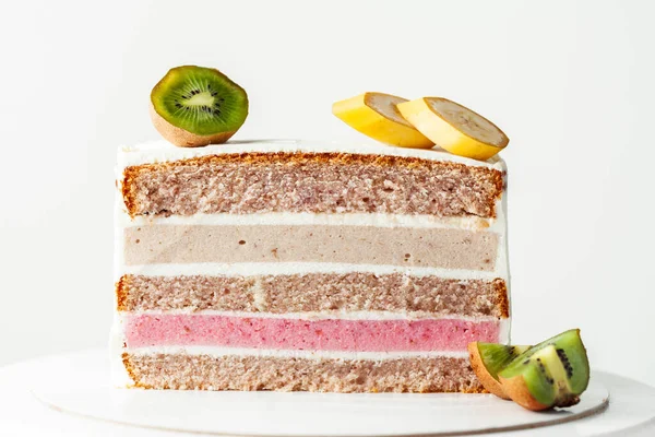 Fruit cake cut on the white background.  Sponge biscuit and fruit mousse layered cake. Tropical fruit cake