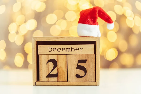 Wooden calendar of blocks with the date of December 25 on the Christmas and New Year blurred background. Beautiful warm light bokeh. Merry Christmas mood.