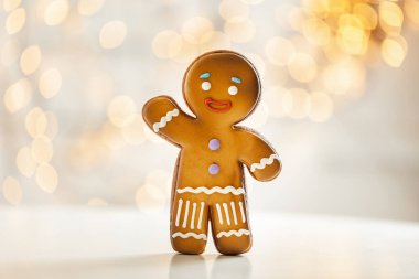 Bulanık Noel ışıkları arka planında zencefilli kurabiye. Sıcak bokeh ışıkları. Makro atış. Yılbaşı ve kış tatili geçmişi. Kış kahve zamanı.