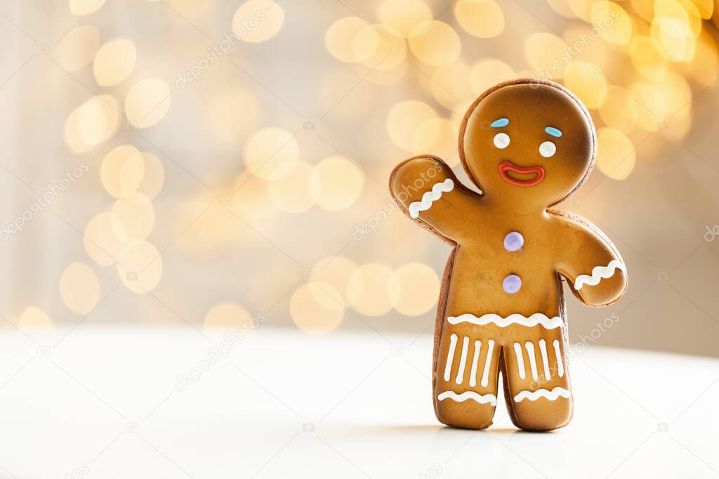 Gingerbread man cookie on the blurred Christmas lights background. Warm bokeh lights. Macro shot. New Year and winter holidays background. Winter coffee time