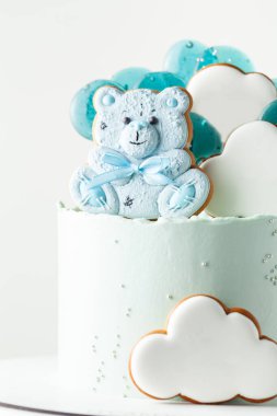 Yeni doğmuş bir çocuk için mavi doğum günü pastası. Oyuncak ayı şeklinde zencefilli kurabiye. Bulut şeklinde zencefilli kurabiyeler, beyaz kremalı ve metnin için boş bir alan. Bebek partisi için kek.
