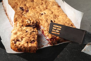 Pasta ızgarasında çilekli streusel turta. Siyah arka planda elmalı turta. Pişirme kağıdında ev yapımı taze turta