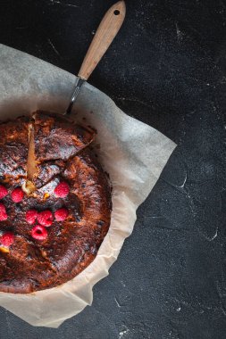 Parşömenin üzerinde fırından yanmış peynirli kek ya da siyah arka planda fırın kağıdı. Başarısız başarısız turta.