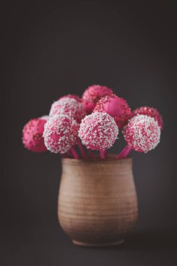 Pembe çikolatalı kek, eskimiş arka plandaki kırsal kahverengi fincanda patlıyor. Bisküvi keki üzerine hindistan cevizi parçacıkları serpiştirilmiş. Sevgililer Günü