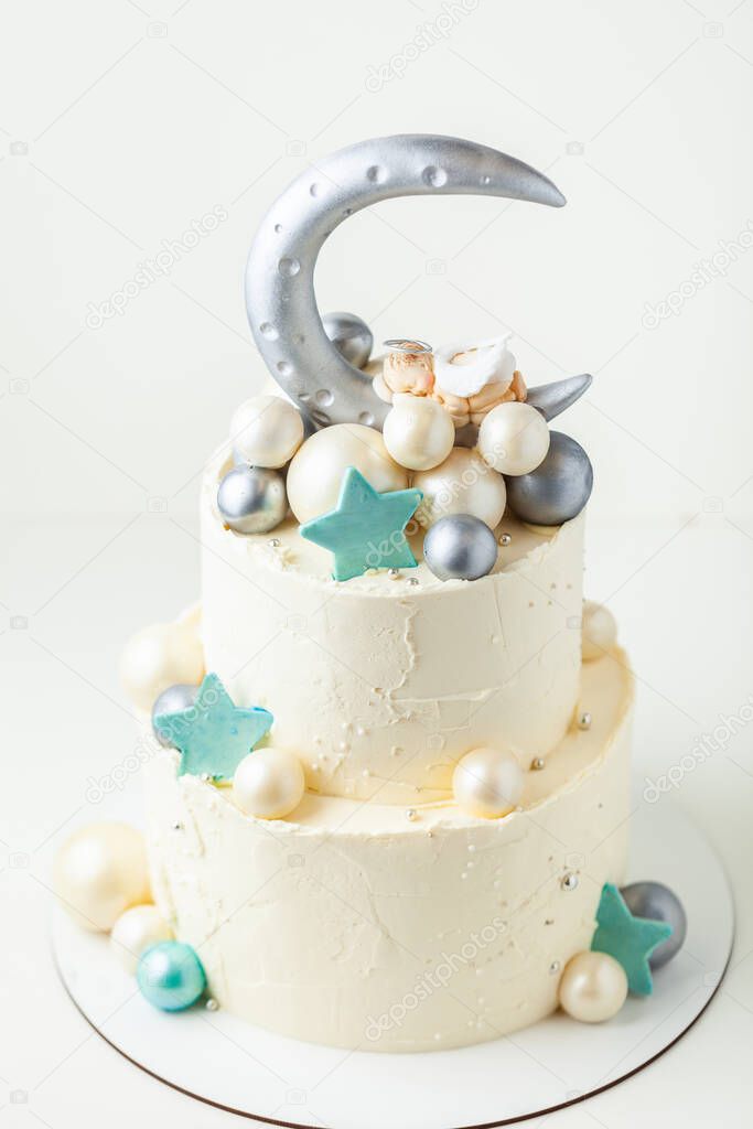 Christening cake with little baby angel sleeping on top. Bunk cake for newborn celebration with the silver moon and spheres made of chocolate decoration