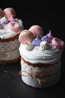 Paskalya pastası, beyaz şeker kreması, krema ve kurabiye ile süslenmiş tatlı ekmek. Kulich karanlık arka planda bir el işi kağıdına sarılmış..