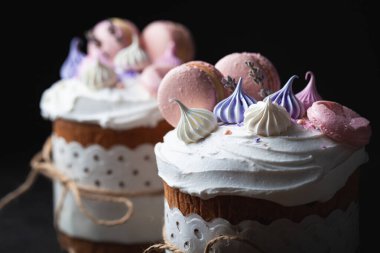 Paskalya pastası, beyaz şeker kreması, krema ve kurabiye ile süslenmiş tatlı ekmek. Kulich karanlık arka planda bir el işi kağıdına sarılmış..