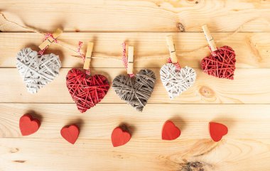 Ahşap arka planda tahta mandallara asılı samandan yapılmış çok renkli kalpler. Sevgililer Günün kutlu olsun. Sevgi ve selamlama metni için boş alan.