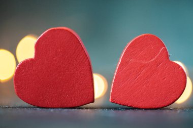 Bulanık beton arka planda iki kırmızı kalp. Arkadaki sarı bokeh ışıkları. Sevgililer Günün kutlu olsun. Aşk konsepti.