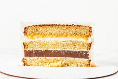 Pastayı süngerle kes. Yumuşak karamelli, limonlu ve krem peynirli pasta beyaz arka planda.