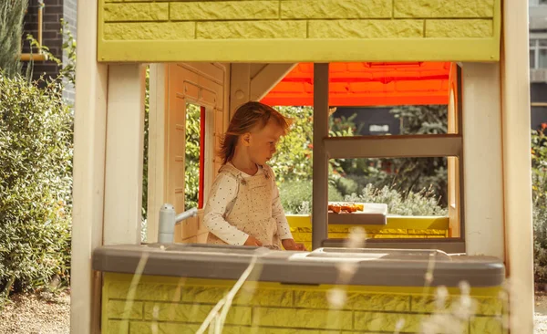 遊び場でおもちゃの台所で遊んでいる幸せな小さな白人の女の子 晴れた日 — ストック写真