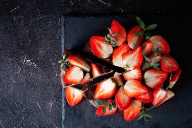 Siyah arka planda çikolata damlayan üç çikolatalı pasta. Sütlü, üstünde çilek desenli siyah beyaz çikolatalı pasta. Kopya alanı olan şekerleme arkaplanı