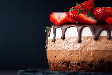 Siyah arka planda çikolata damlayan üç çikolatalı pasta. Sütlü, üstünde çilek desenli siyah beyaz çikolatalı pasta. Kopya alanı olan şekerleme arkaplanı