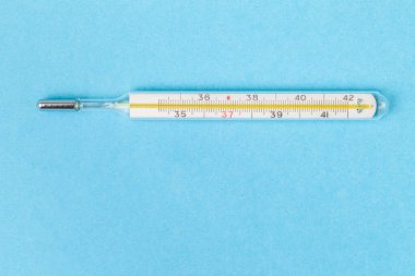 Tıbbi cıva termometrenin makro görüntüsü. Eski ve yeni prensibi. Mavi arka planda modası geçmiş termometre. Metin için boş alanı olan düz bir yer. Vücut sıcaklığı ölçme aygıtı