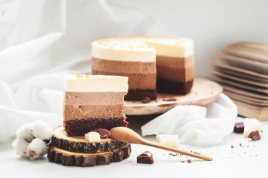 Beyaz arka plandaki ahşap tezgahta üç katmanlı çikolatalı mus keki. Taze kahve ve çikolatalı sufle ile günaydın. Eski arkaplan